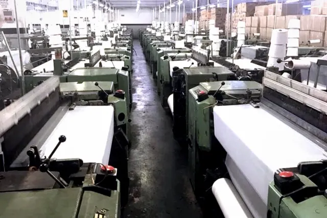 Şal üretim fabrikasında sıra sıra dizilmiş modern dokuma makineleri